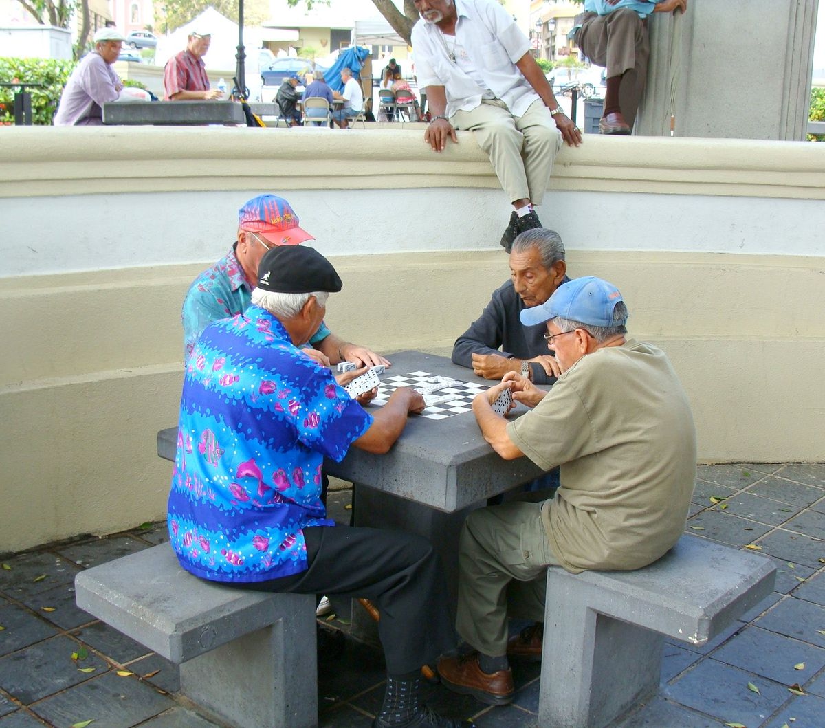 Four men playing dominoes at an outdoor concrete table in San Juan, Puerto Rico
